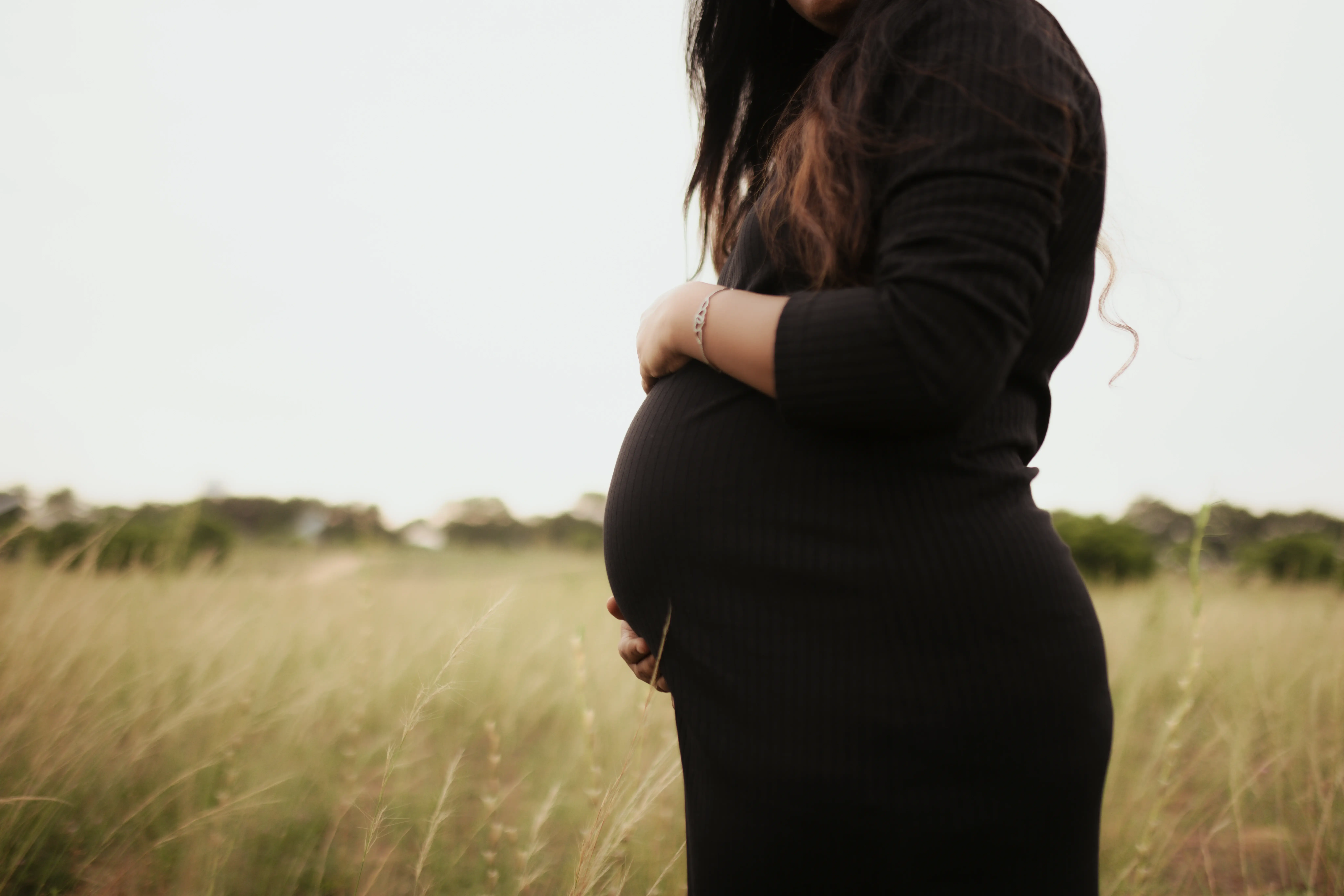 Pregnancy photoshoot with a mother holding ultrasound images and smiling in studio.