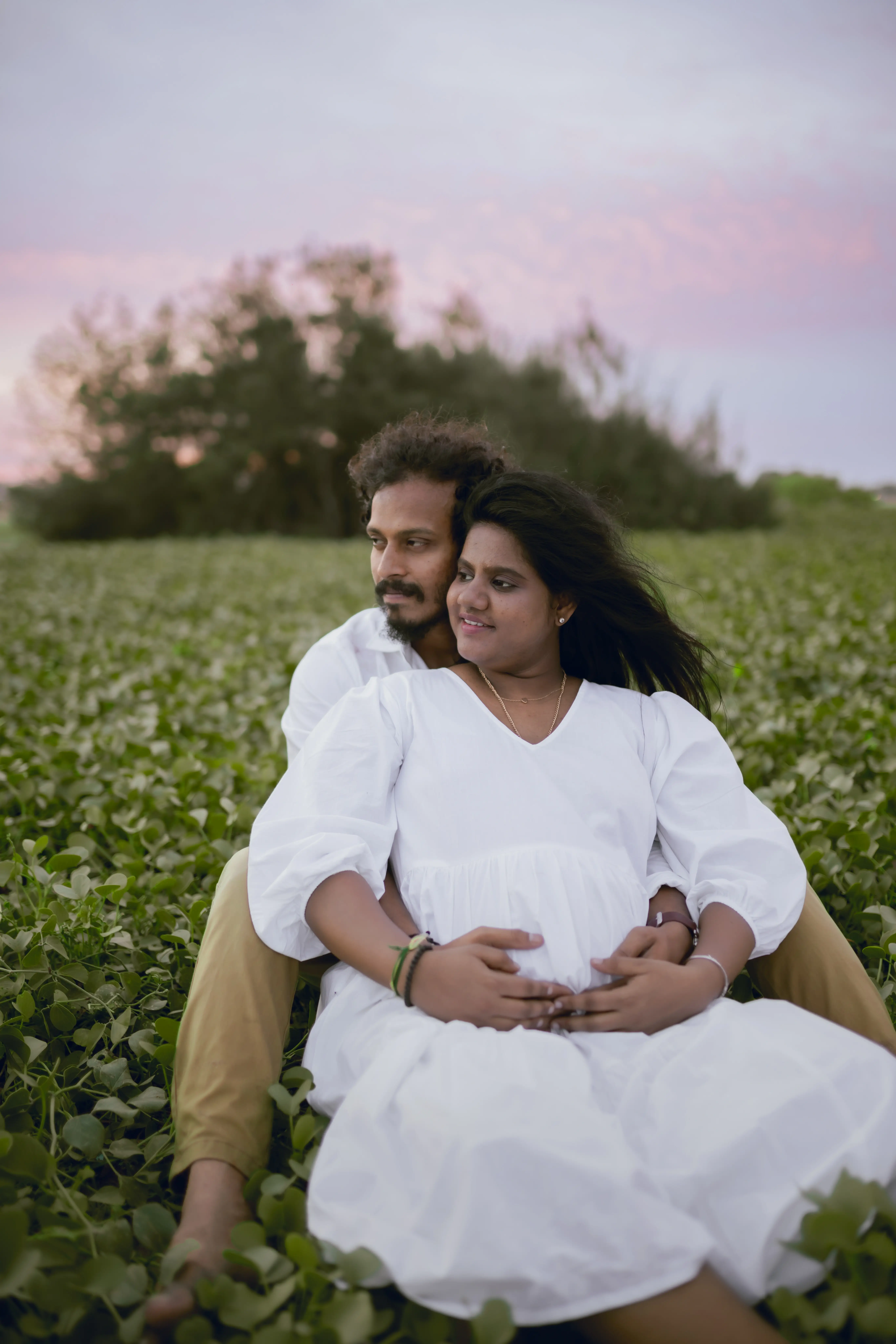 Outdoor photo shoot for a pregnant woman standing peacefully with her hands on her baby bump.
